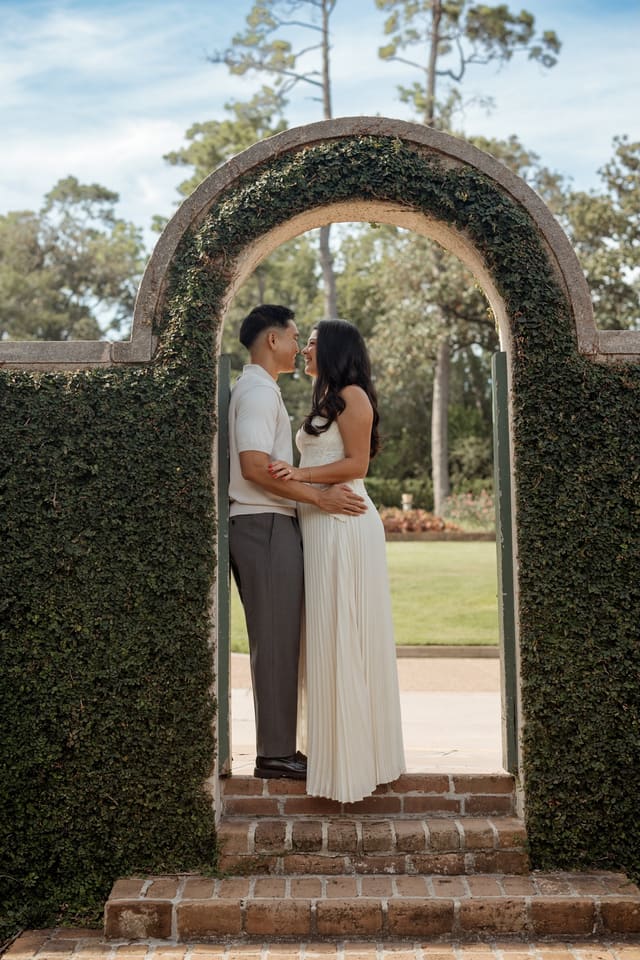 Julian and Genesis kissing beneath an ivy-covered garden arch