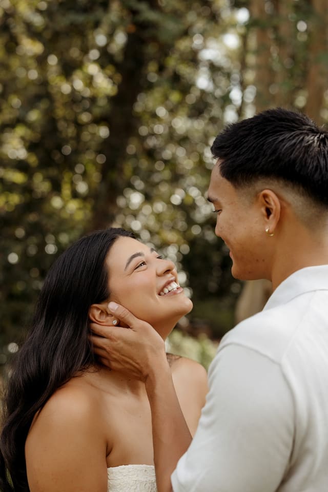 Close-up of Julian cupping Genesis's face as they both smile